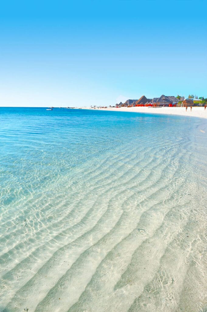 Bravo Premium Kendwa Beach offre un'esperienza serena sulla spiaggia con acqua cristallina e un ambiente vivace grazie alla presenza di persone.