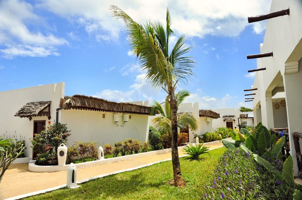 Un edificio bianco con una palma di fronte a Bravo Premium Kendwa Beach.