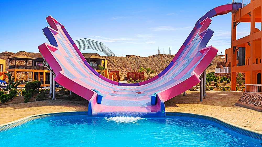 Un vivace acquascivolo rosa con design half-pipe nel parco acquatico all'aperto del Villaggio Mar Rosso.