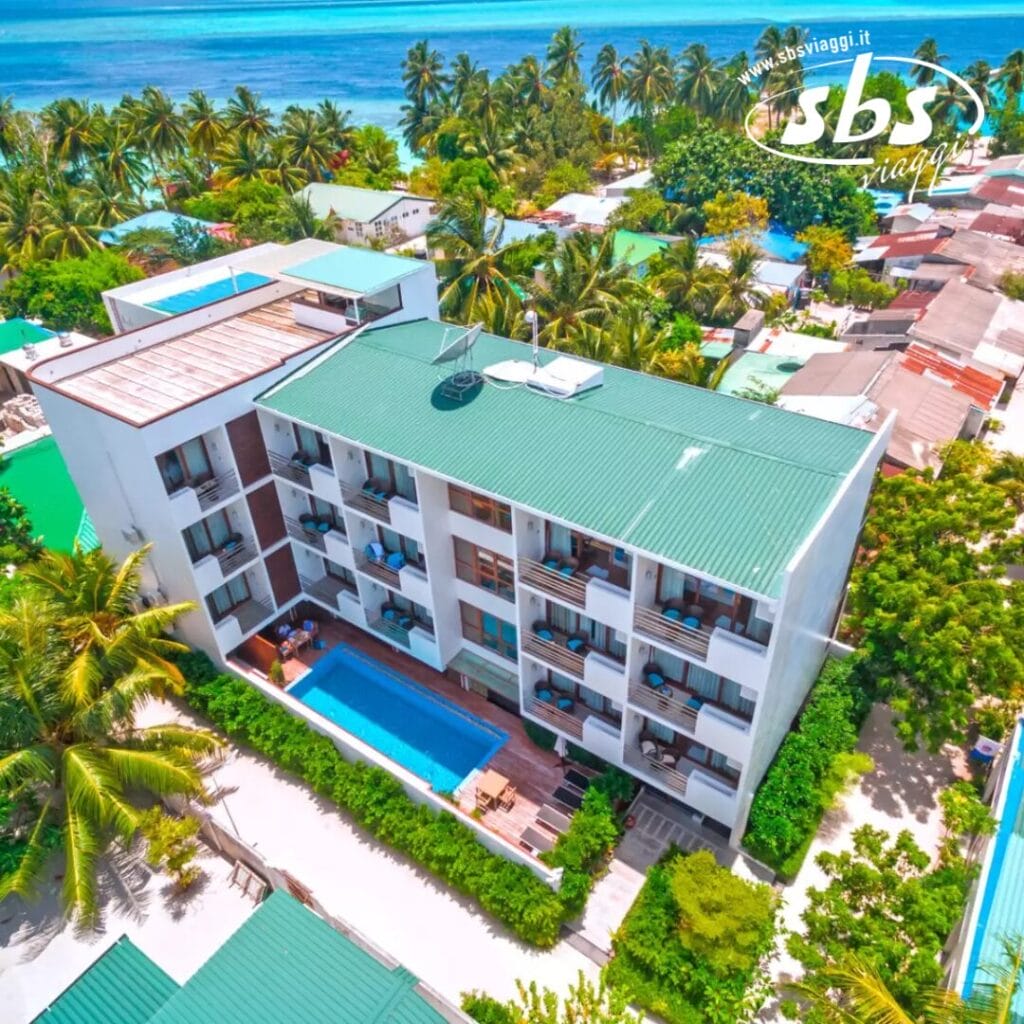 Vista aerea del Plumeria Hotel, un rifugio di tre piani con tetto verde, balconi e una piscina scintillante, incastonato tra palme e edifici vicini vicino all'oceano.