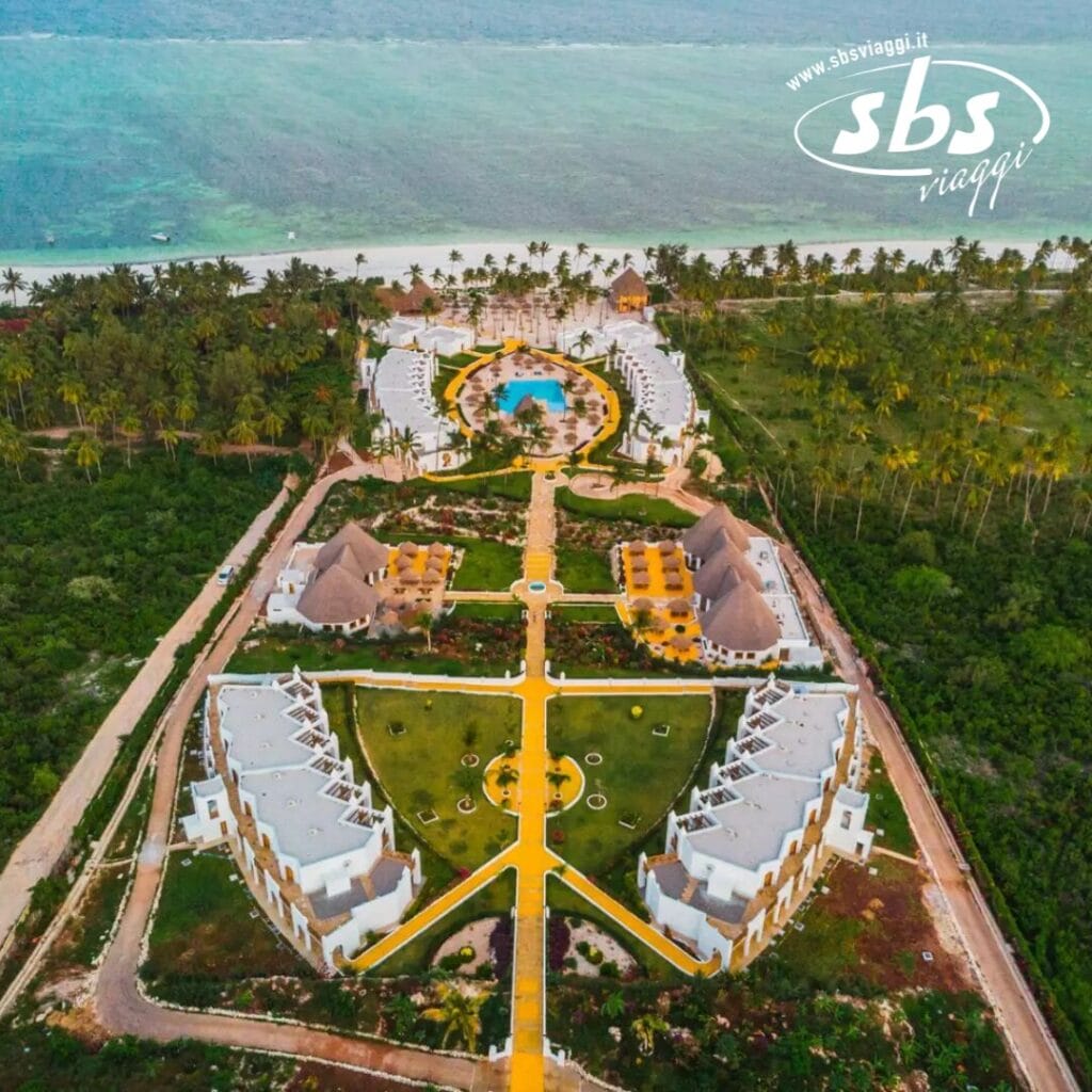 Vista aerea dello Sbh Kilindini Resort che mostra i suoi numerosi edifici, una piscina centrale e un lussureggiante paesaggio verdeggiante sulla spiaggia e sull'oceano. Il logo