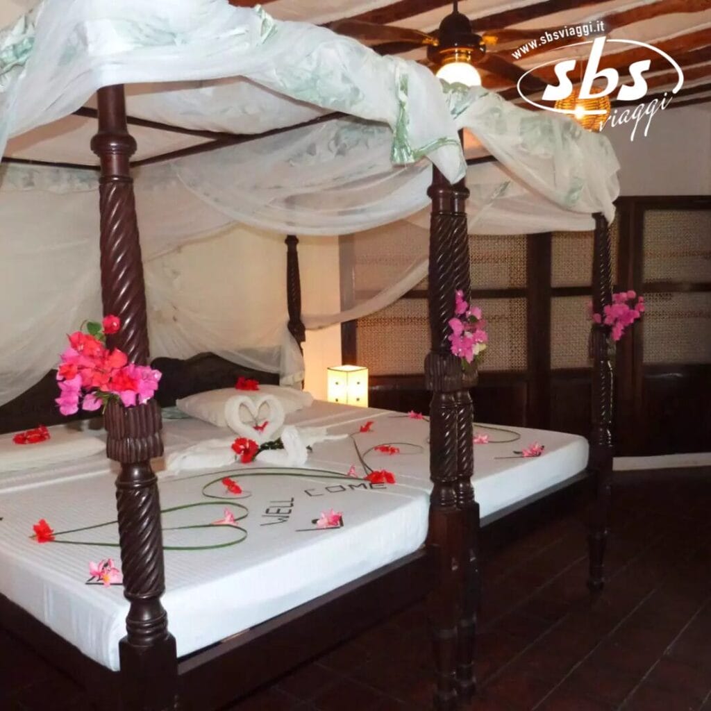 Un letto a baldacchino decorato, decorazioni floreali e asciugamani piegati a forma di cigno su un lenzuolo bianco creano un'atmosfera invitante in questo affascinante resort internazionale.