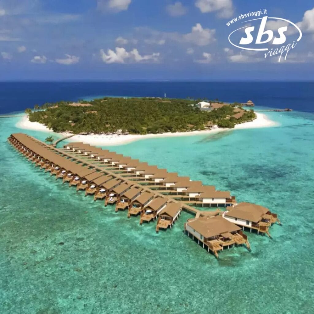 Vista aerea del Reethi Faru Resort, che mette in mostra i suoi bungalow sull'acqua e le spiagge di sabbia bianca circondate da un oceano azzurro e limpido.