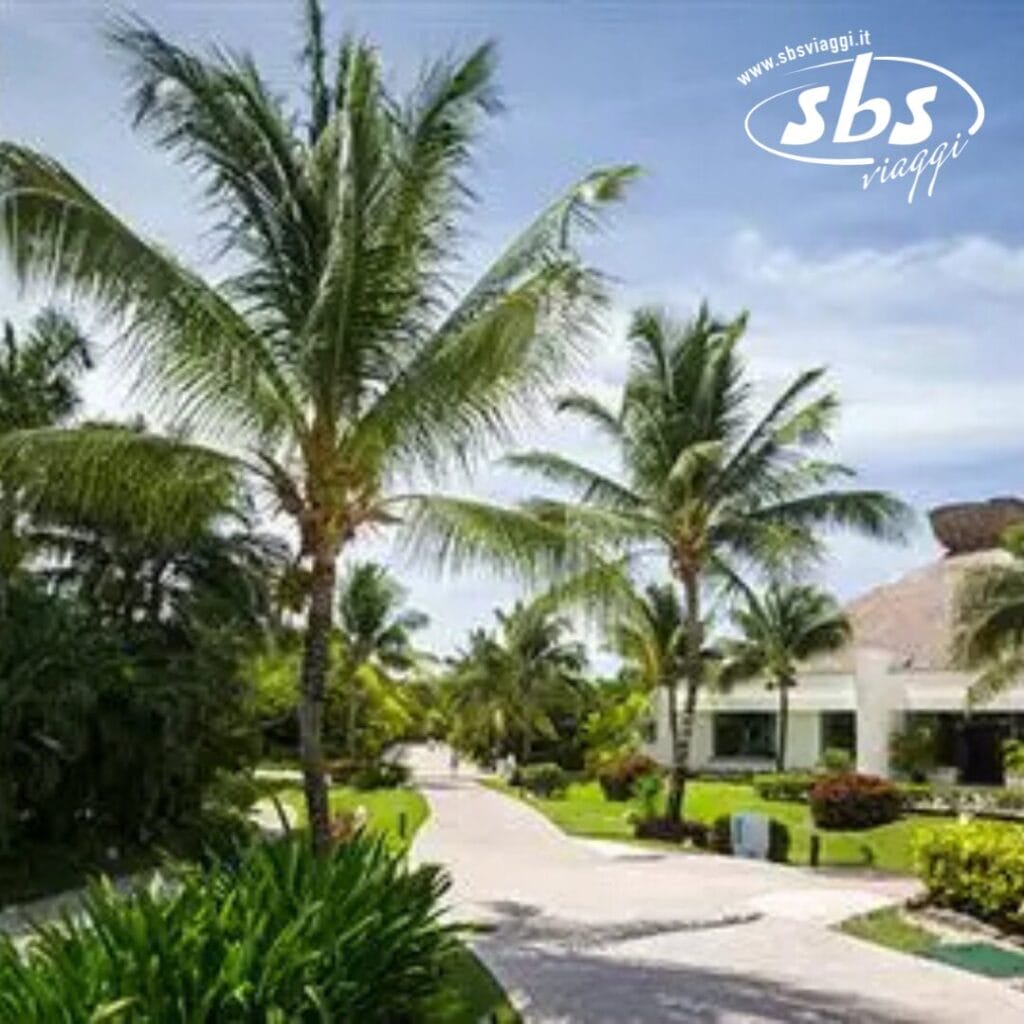 Resort tropicale con palme, sentieri tortuosi e un edificio bianco immacolato. Nell'angolo, il logo recita