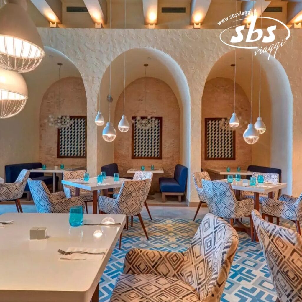 L'elegante interno del ristorante vanta sedie con motivi e tavoli bianchi, illuminati da lampade a sospensione. Nicchie ad arco e piastrelle geometriche sul pavimento esaltano l'atmosfera moderna, mentre la bozza automatica fonde perfettamente la tradizione con il design contemporaneo.