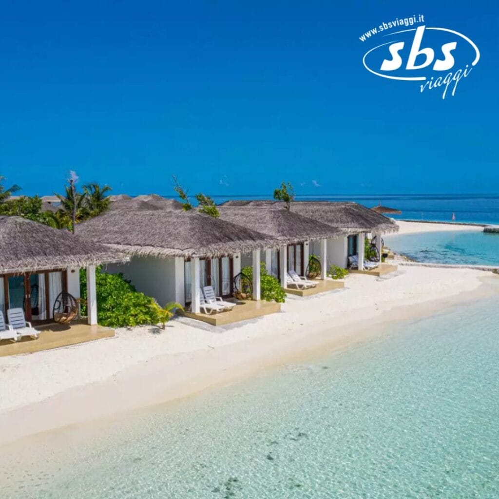 I bungalow fronte mare del Cocogiri Island Resort sono dotati di tetti di paglia e sedie a sdraio, posizionati in modo perfetto per ammirare le limpide acque turchesi sotto un cielo azzurro brillante.