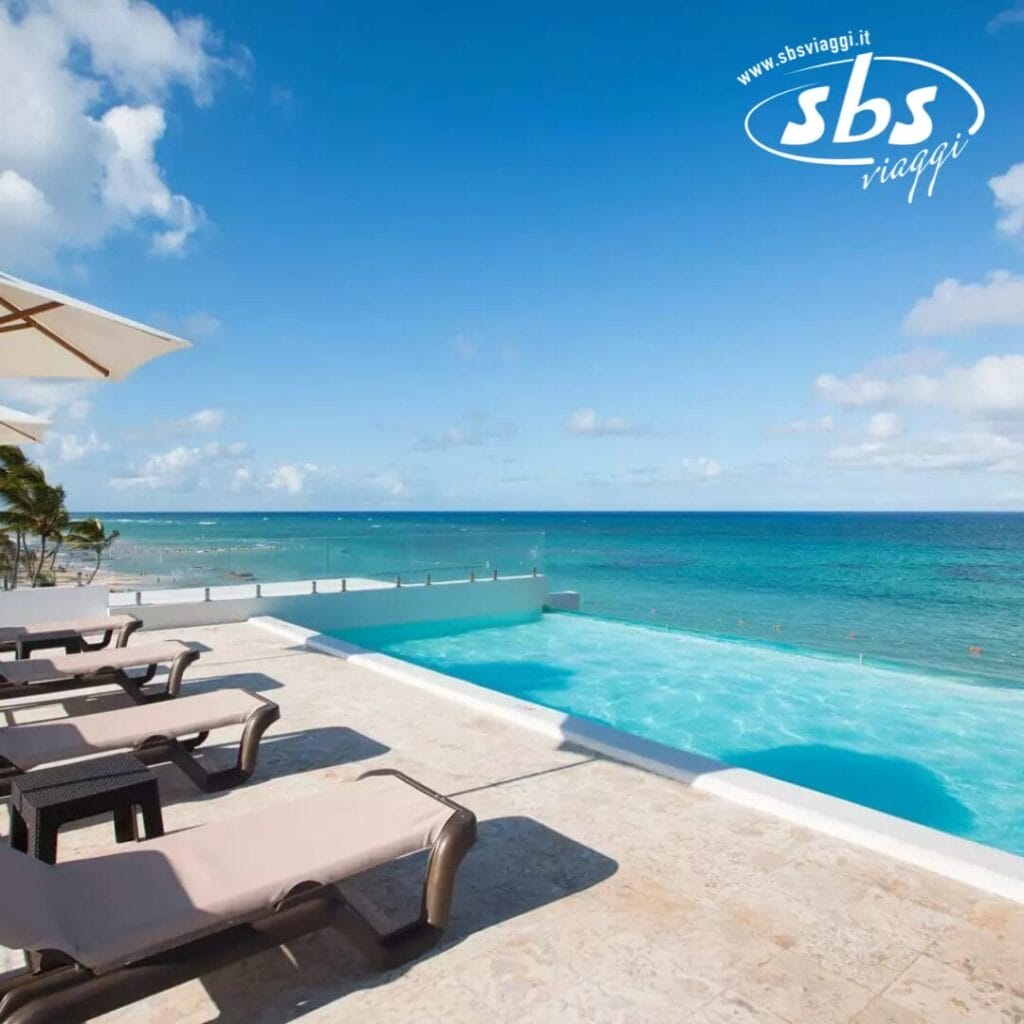 Provate il lusso sereno della piscina a sfioro del Whala! Bavaro, dove le sedie a sdraio vi invitano a rilassarvi sotto un cielo azzurro e limpido, mentre ammirate il vasto oceano.