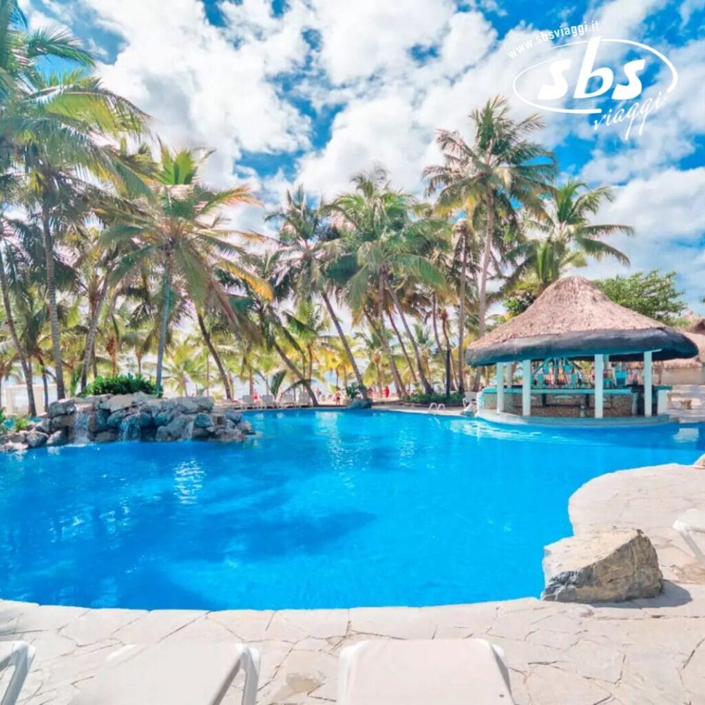Il resort sulla spiaggia Coral Costa Caribe offre una piscina tropicale circondata da palme, un bar con tetto di paglia e cieli azzurri infiniti. Sedie da spiaggia bianche costeggiano il primo piano, invitandoti a rilassarti e a immergerti nell'atmosfera serena.