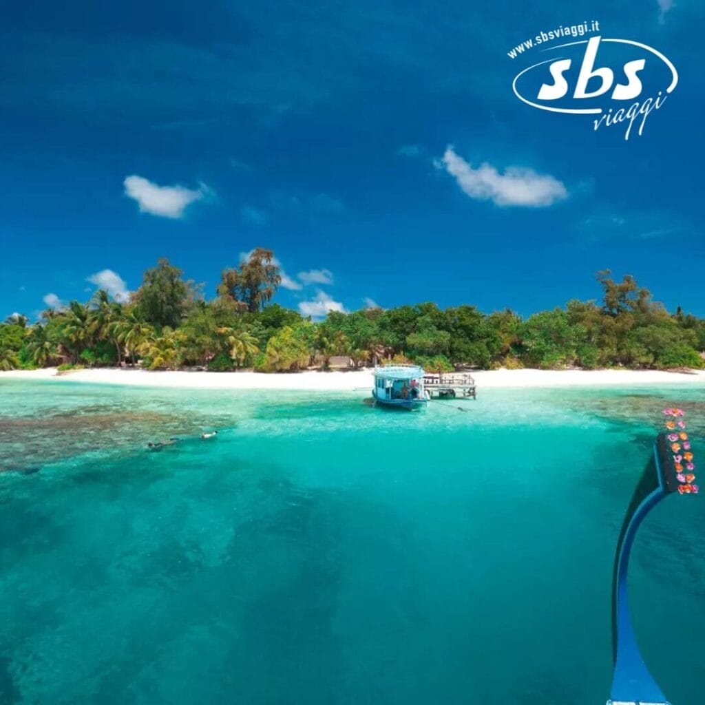 Una piccola imbarcazione si avvicina a un'isola tropicale, guidata dolcemente dalla bozza automatica verso la vegetazione lussureggiante e la spiaggia sabbiosa, sotto un cielo azzurro e terso.