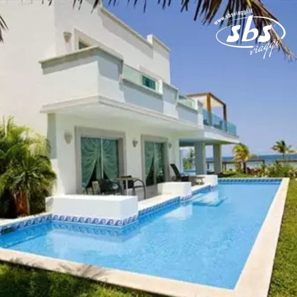 Moderna casa sulla spiaggia con piscina, circondata da palme e di fronte all'oceano: un perfetto esempio di lusso tropicale.