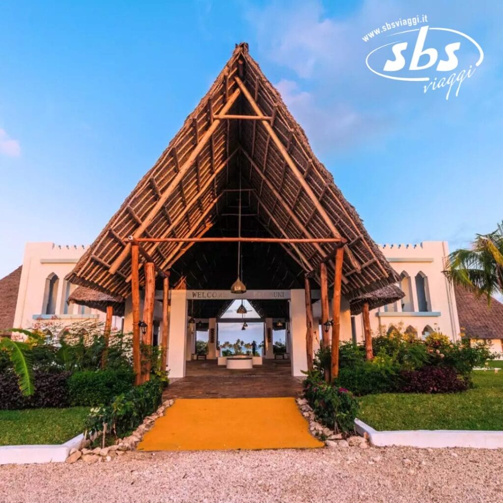 L'ingresso del Kilindini Resort con il tetto di paglia, incorniciato da legno pregiato e circondato da una vegetazione lussureggiante, accoglie calorosamente gli ospiti con il cartello