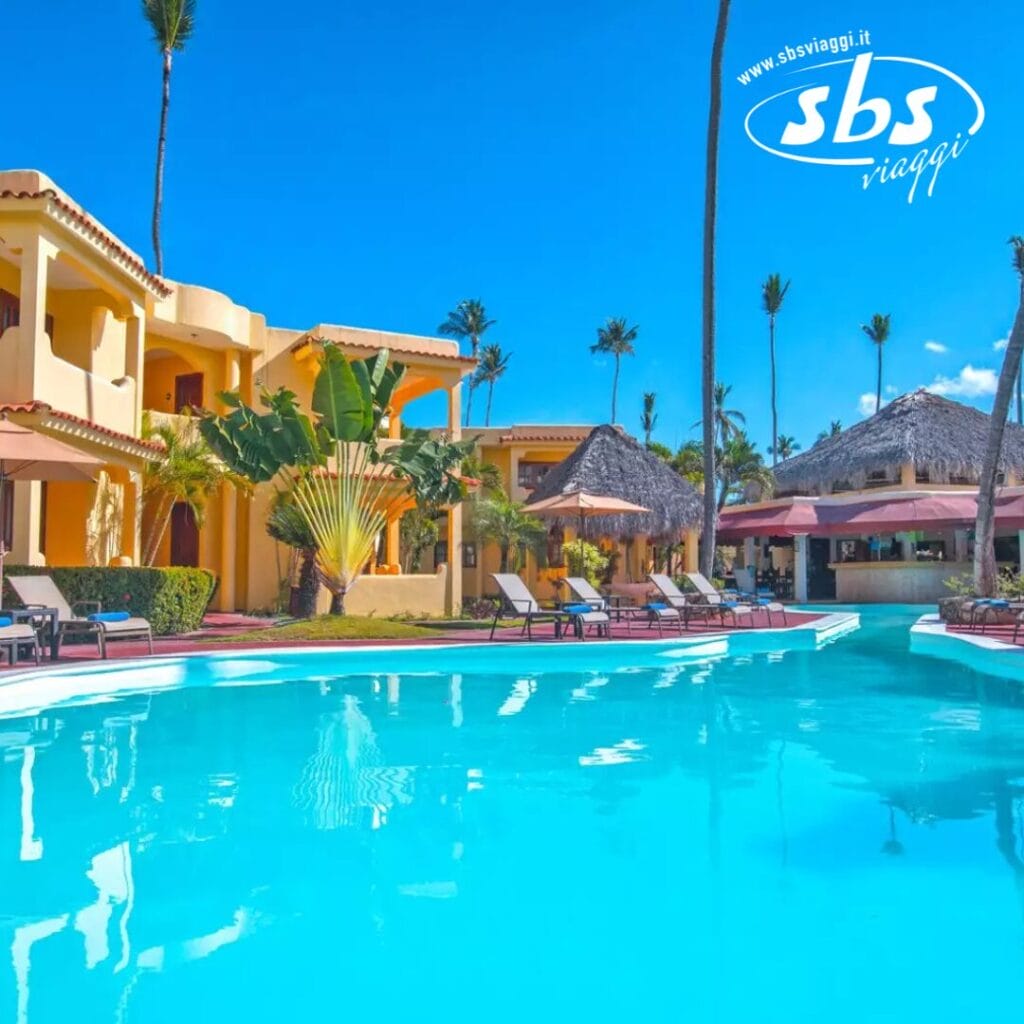 La piscina del Whala! Bávaro di fronte al resort tropicale è incorniciata da palme, sedie a sdraio e strutture con tetto di paglia sotto un cielo azzurro e terso.