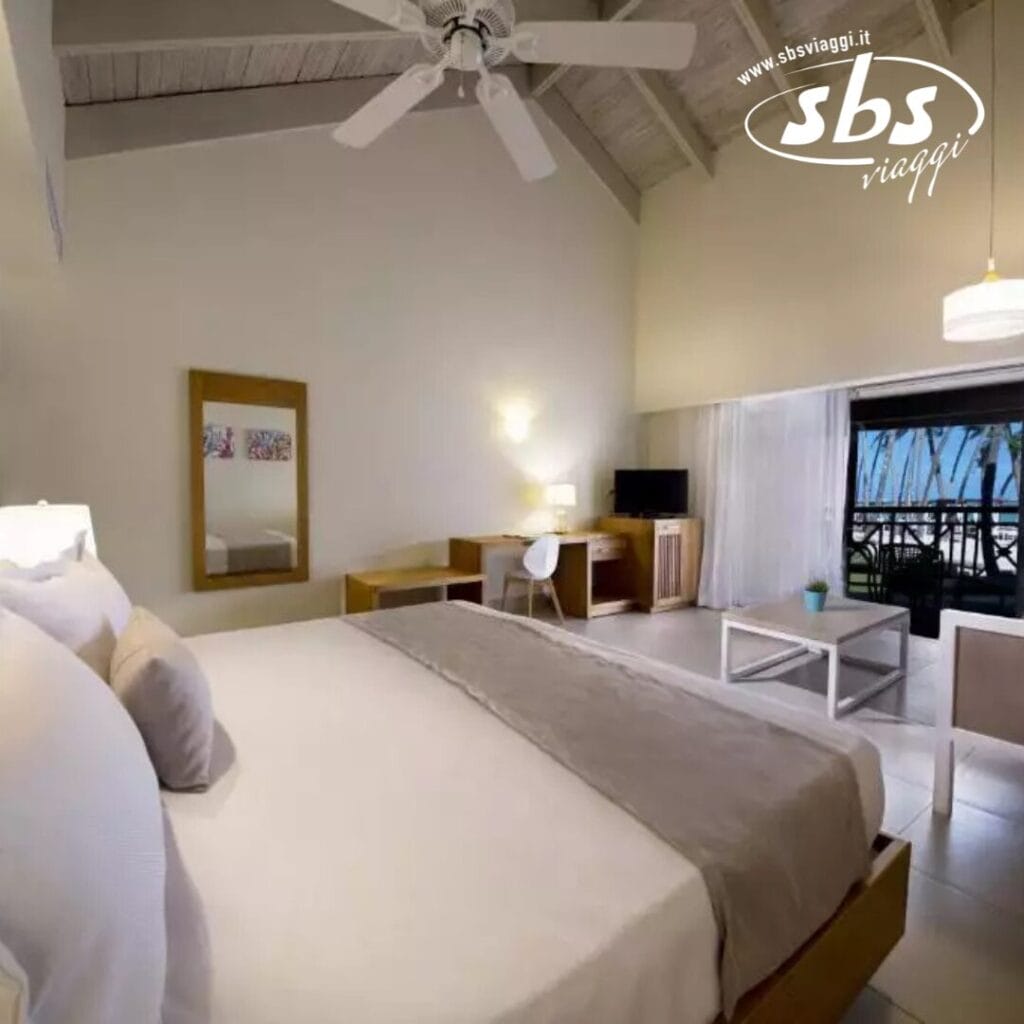 Rilassati in una camera d'albergo Vista Sol con un grande letto, scrivania e sedia. Goditi il balcone con vista sulle splendide palme di Punta Cana e sull'oceano. Ventilatore a soffitto e lampade forniscono un'illuminazione perfetta. Vivi l'atmosfera tranquilla di questo resort sulla spiaggia di prima qualità.