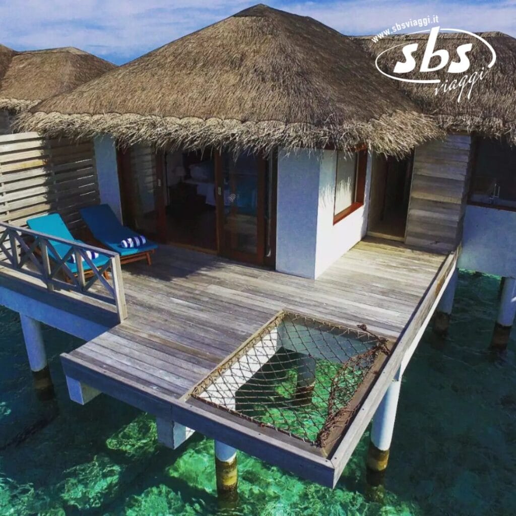 Vivi la magia di un bungalow sull'acqua del Cocogiri Island Resort, dotato di tetto di paglia, terrazza in legno, due sedie a sdraio e una zona con rete, il tutto a picco sulle acque cristalline e turchesi.