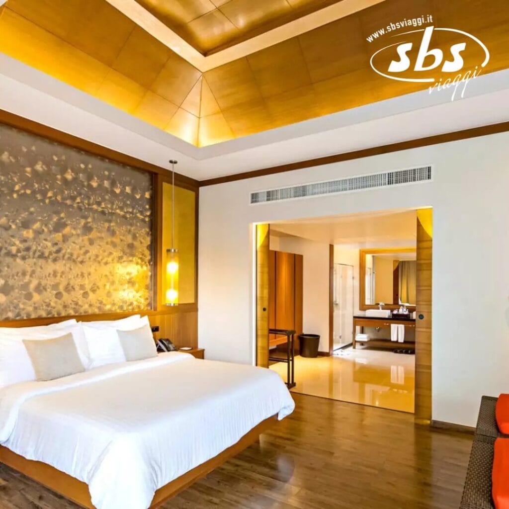 Una lussuosa camera d'albergo con un letto grande, pavimento in legno e un bagno moderno. Il soffitto color oro crea un'atmosfera calda. Un tocco delicato del marchio