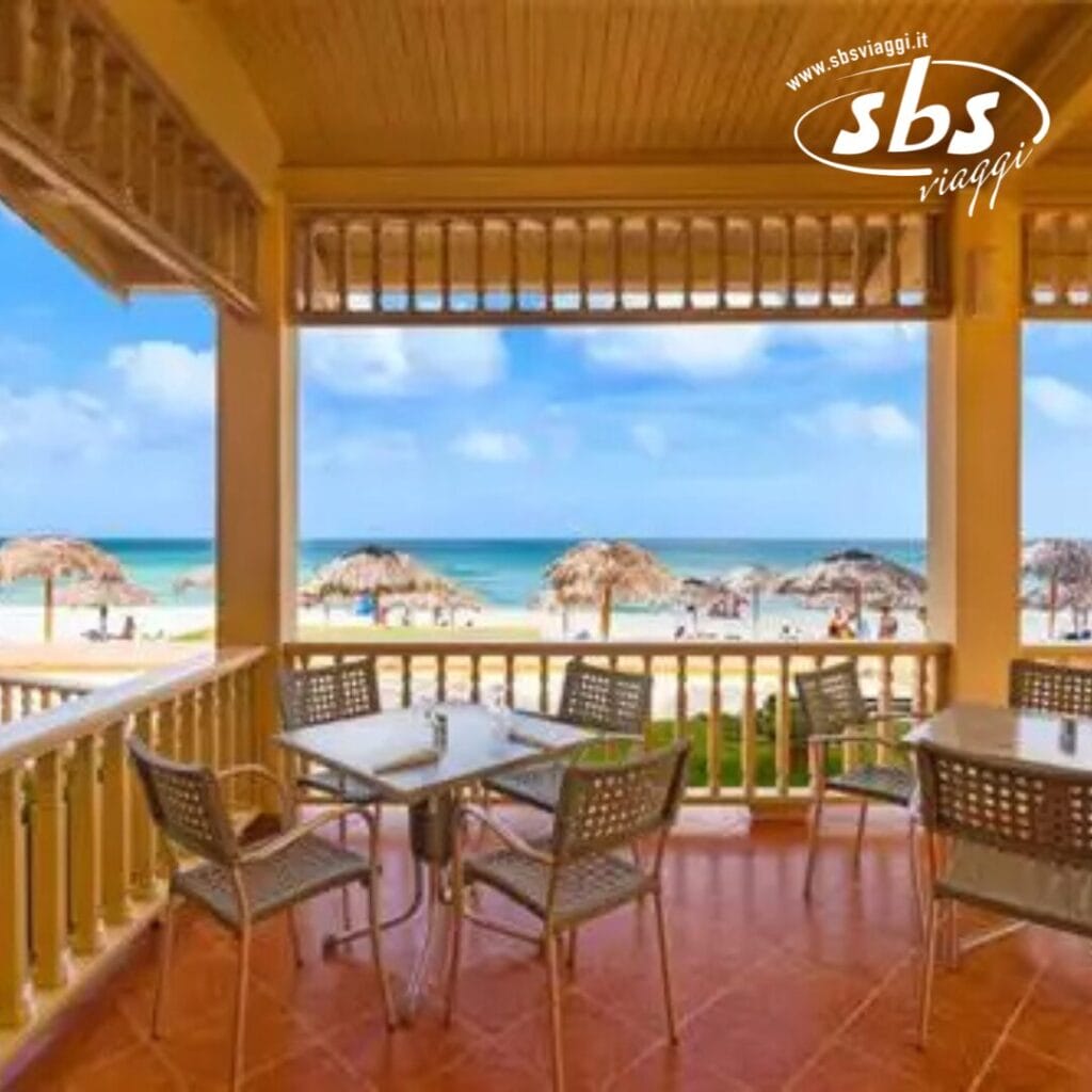 Da un patio coperto con tavoli e sedie, godetevi una vista serena della spiaggia adornata da ombrelloni di paglia. L'iconico logo