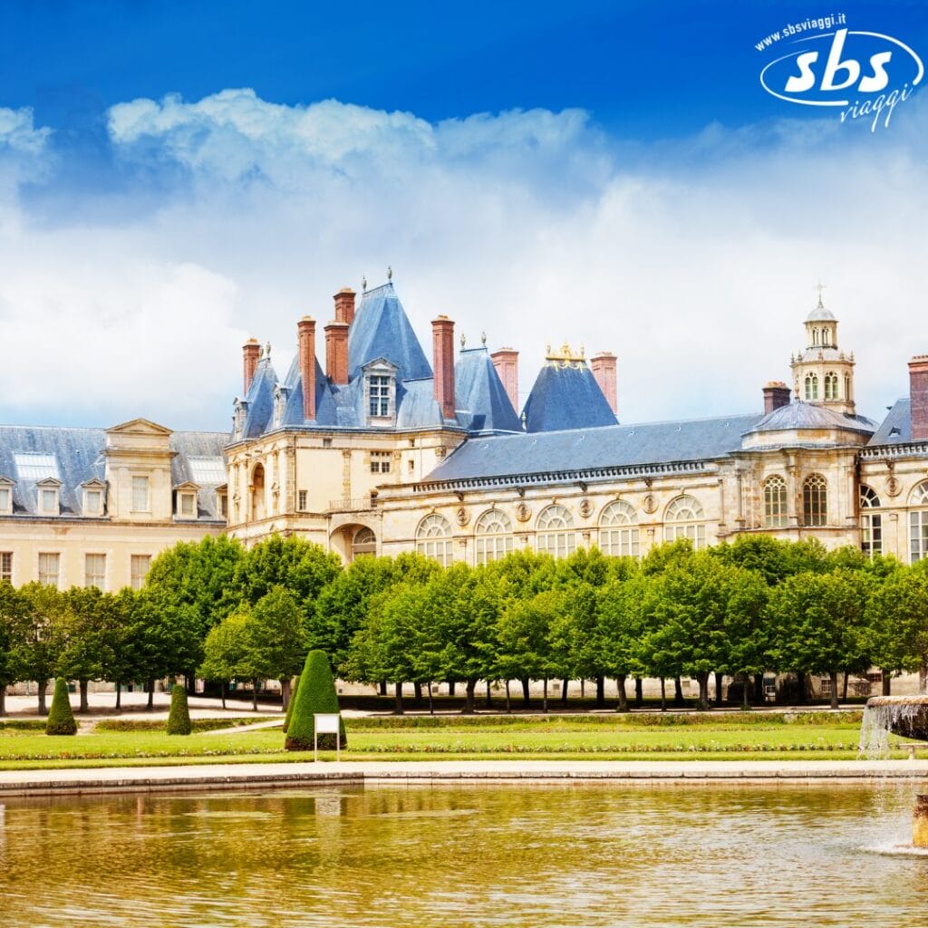 Adagiato su uno specchio d'acqua riflettente, lo storico castello vanta tetti blu, numerosi camini e finestre ornate. Una fila di alberi incornicia questa scena incantevole sotto un cielo parzialmente nuvoloso, una pittoresca bozza automatica di eleganza e natura in armonia.