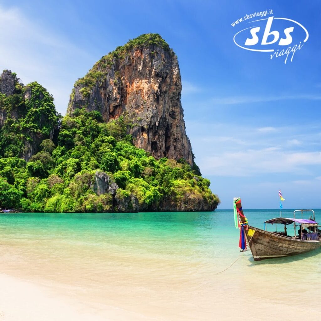 Una barca tradizionale in legno è ancorata su una spiaggia sabbiosa con acqua turchese e limpida, che ricorda una scena di una Bozza automatica. Una ripida e verdeggiante scogliera si erge sullo sfondo sotto il cielo azzurro e limpido.