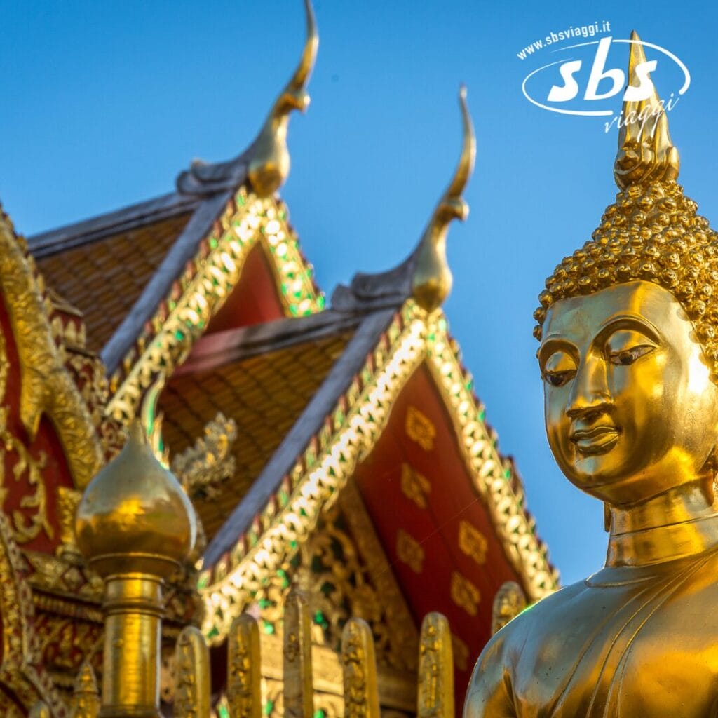 La statua del Buddha dorato si erge maestosa di fronte al tetto decorato di un tempio, mettendo in mostra dettagli intricati contro un cielo azzurro terso: un vero capolavoro di Bozza automatica.