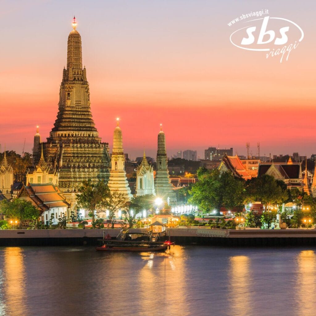 La Bozza automatica del tempio Wat Arun risplende al tramonto, adagiata con grazia lungo il fiume, con una barca lì vicino, circondata da altri edifici illuminati sotto un cielo limpido.
