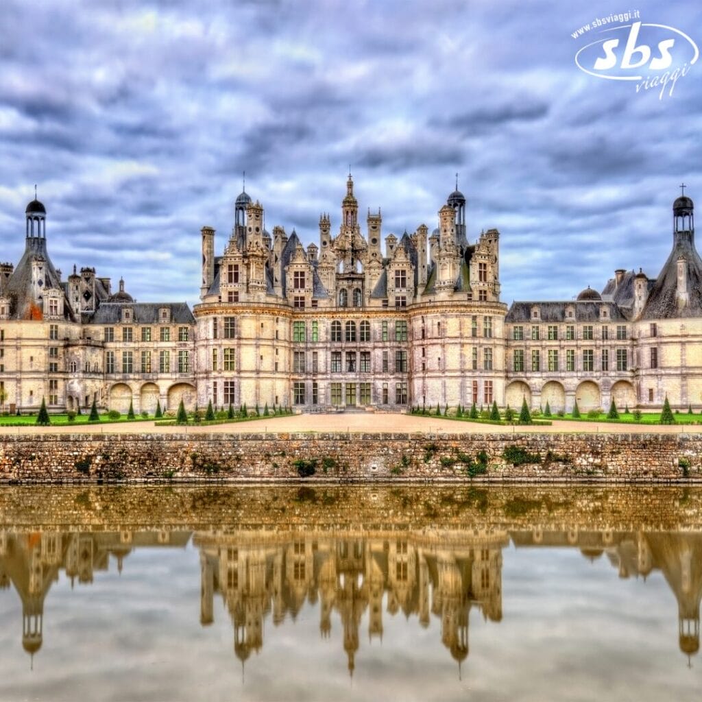 Castello storico con numerose torri e architettura elaborata, la cui immagine si specchia con grazia nelle acque calme sotto un cielo nuvoloso, emanando un'atmosfera quasi magica, simile a quella di una bozza automatica che cattura una bellezza senza tempo.