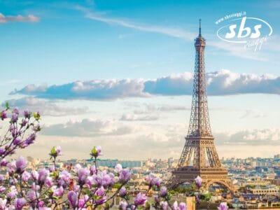 La Torre Eiffel adorna il cielo azzurro con le sue nuvole, circondata da fiori di magnolia in fiore. Il logo di SBS Viaggi nell'angolo in alto a destra, evoca sogni non solo di Parigi ma anche degli incantevoli Castelli della Loira.