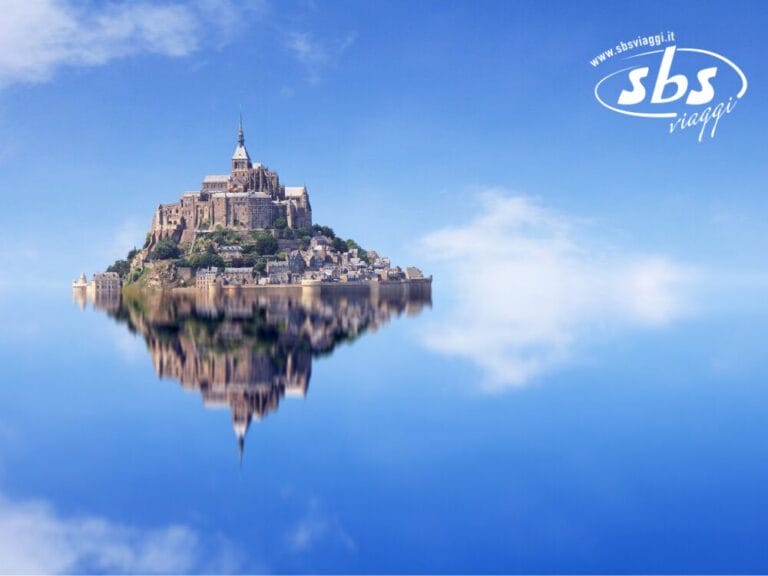 L'isola e l'abbazia di Mont Saint-Michel si specchiano magnificamente nelle calme acque azzurre della Normandia, sotto un cielo limpido, con il logo SBS Viaggi elegantemente posizionato in un angolo.