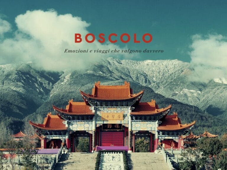 Un tempio cinese tradizionale con tetti rossi, montagne innevate sullo sfondo e il testo di viaggio "Boscolo" sopra: uno scorcio invitante sull'incantevole Gran Tour della Cina.