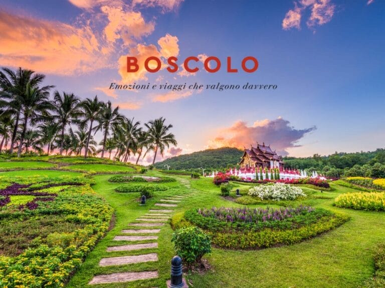 Un rigoglioso giardino con palme, fiori vivaci e un padiglione al tramonto evoca la bellezza della Thailandia e del suo mare cristallino. Testo: Boscolo, emozioni e viaggi.
