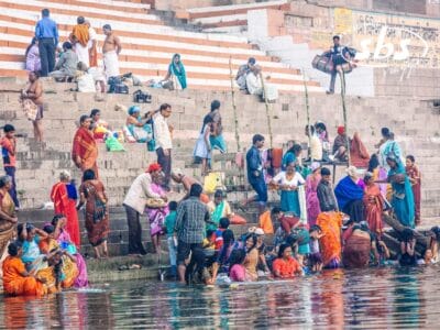 Le persone si riunivano sui gradini di pietra in riva al fiume, dedicandosi ad attività come lavarsi, socializzare e compiere rituali: una scena che ricorda un dipinto di bozza automatica che prende vita.