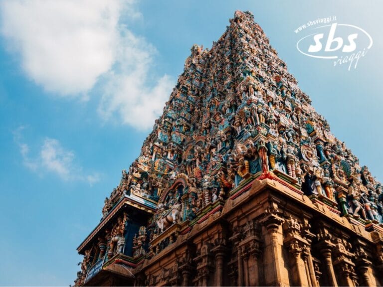 La vivace torre del tempio, ornata da intricate sculture, si erge maestosa contro il cielo azzurro e terso. Vista da un'angolazione bassa, la scena cattura sia l'arte che la tranquillità.
