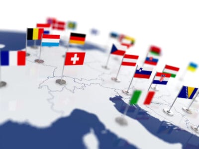 Mappa dell'Europa con piccole bandiere che rappresentano vari paesi, tra cui Francia, Belgio, Svizzera e Germania, posizionate nelle rispettive posizioni.