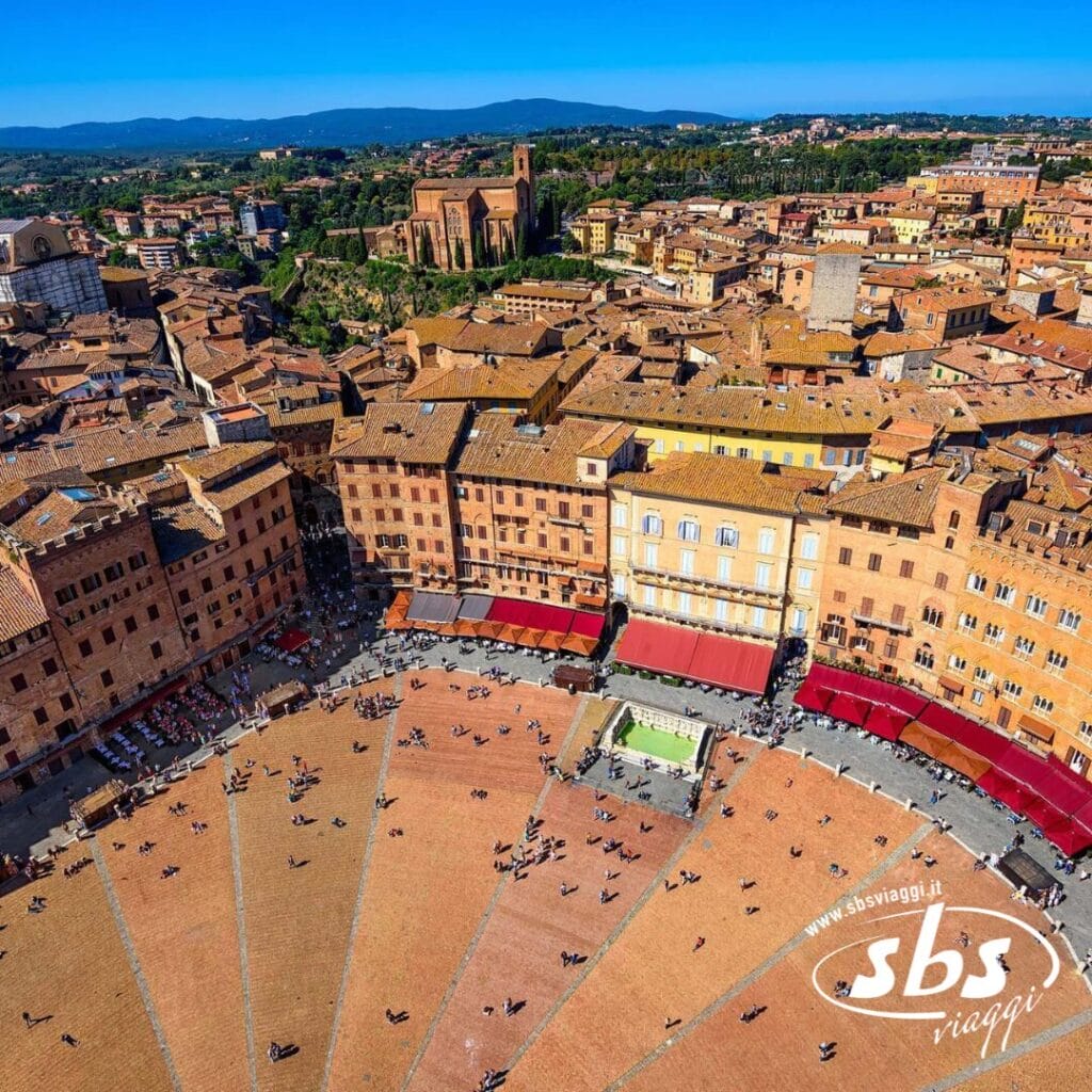 Vista aerea di Piazza del Campo a Siena, Italia, un gioiello della Toscana. La piazza è costellata di edifici storici e persone sparse, catturando l'essenza del fascino italiano. Una tappa obbligata in qualsiasi tour della regione.