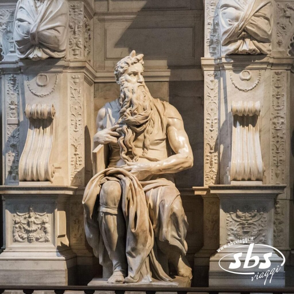 Una statua in marmo di un uomo barbuto siede con grazia, drappeggiato in abiti eleganti, in mezzo all'architettura ornata di Roma. Questa scena iconica vi invita a visitare la bellezza senza tempo e la ricca storia della Città Eterna.