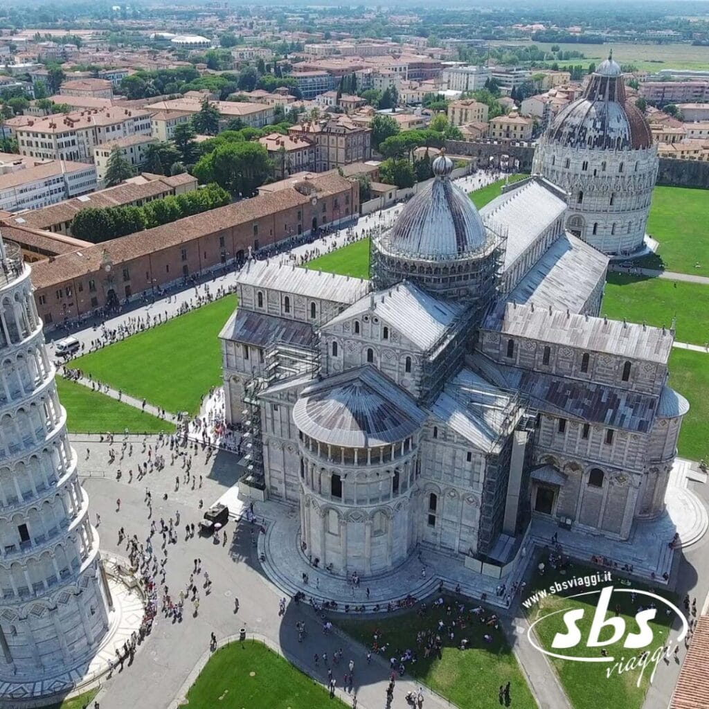 Vista aerea di Pisa, Italia, che mostra l'iconica Torre Pendente, la Cattedrale di Pisa e il Battistero di Pisa tra prati verdi e palazzi storici. Perfetto per chi ha in programma di visitare la Toscana o esplorare gemme vicine come le Cinque Terre.