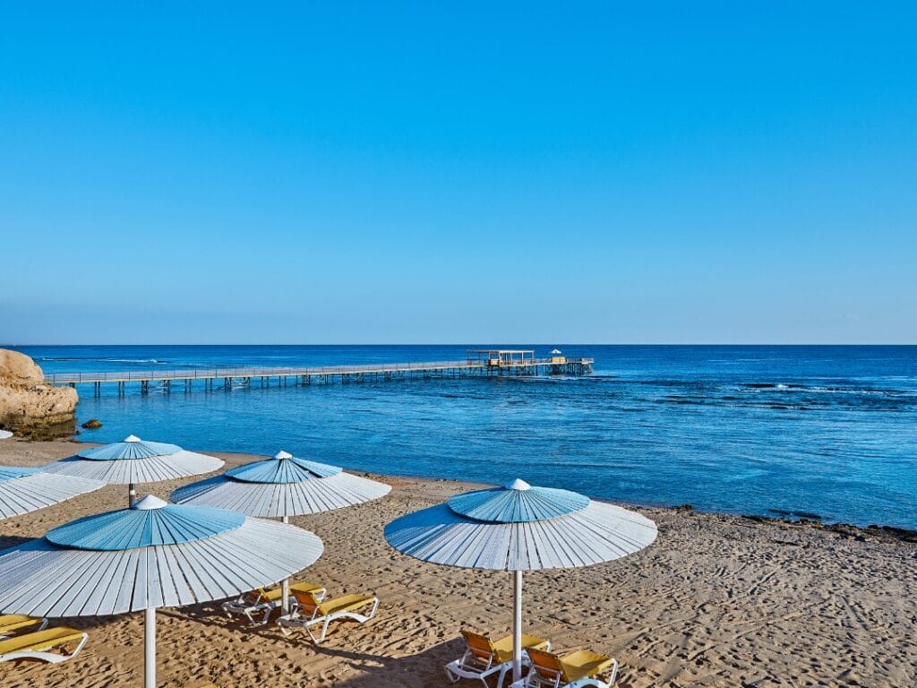 Provate il massimo relax in una scena di spiaggia dove ombrelloni bianchi e sedie a sdraio invitano alla serenità. Che passeggiate lungo il lungo molo o semplicemente vi crogioliate sotto un cielo terso, concedetevi un alloggio di lusso presso l'hotel a 5 stelle JAZ GRAND MARSA, in riva al calmo mare blu.