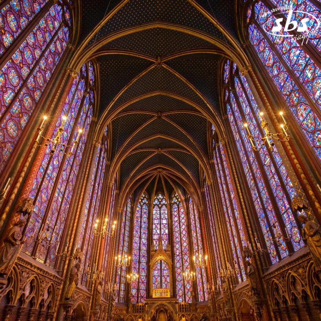 Vista interna di una cappella gotica con alte vetrate colorate, soffitti a volta, decorazioni ad arco e lampadari elaborati: un gioiello nascosto nel tour della Provenza.