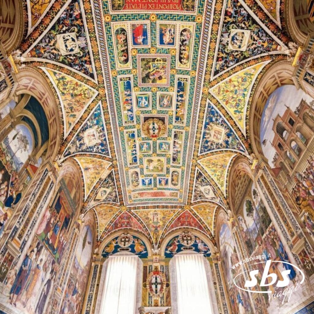 Il soffitto ornato della biblioteca, decorato con dipinti intricati e colori vivaci, mette in mostra personaggi e scene storiche su uno sfondo che ricorda gli incantevoli paesaggi della Val d'Orcia. Le finestre ad arco luccicanti incorniciano questo maestoso capolavoro ispirato a Siena.