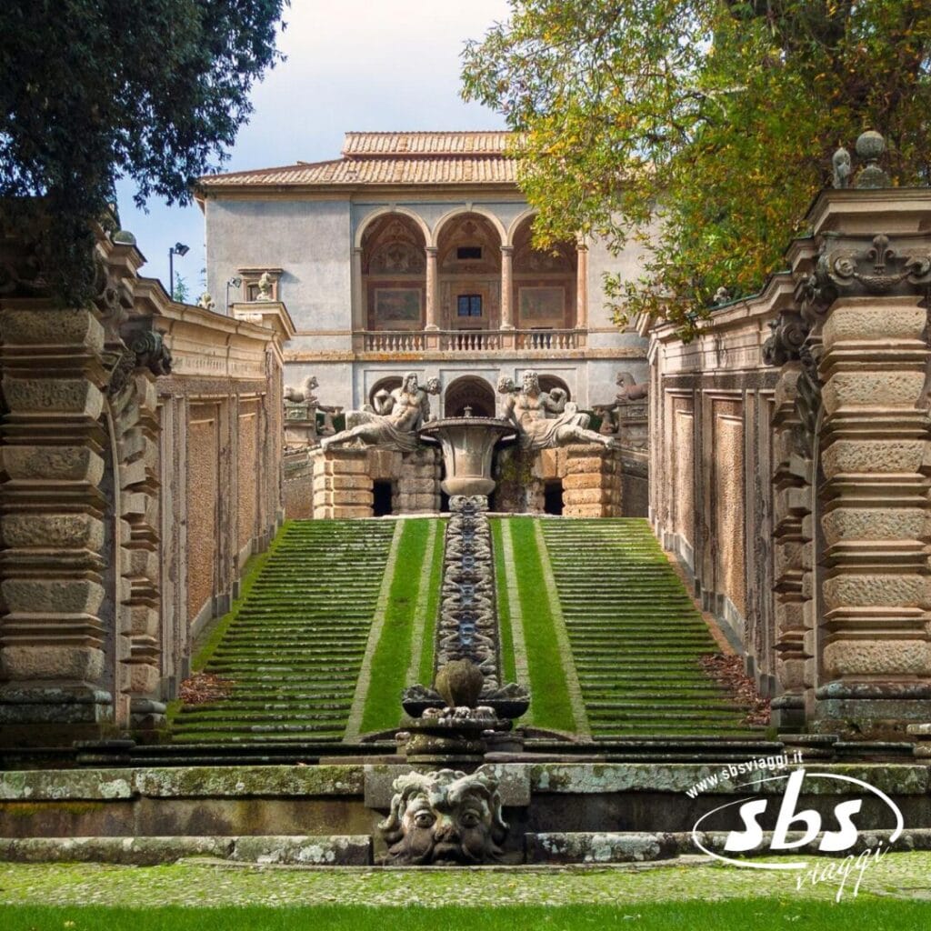 Villa storica con facciata decorata, gradini in pietra e un sentiero fiancheggiato da siepi che conduce a una fontana. Sculture decorative e vegetazione abbondano, ricordando il sorriso dell'Etrusco. Il tutto sotto un cielo nuvoloso tipico delle ambientazioni del Tour della Tuscia.