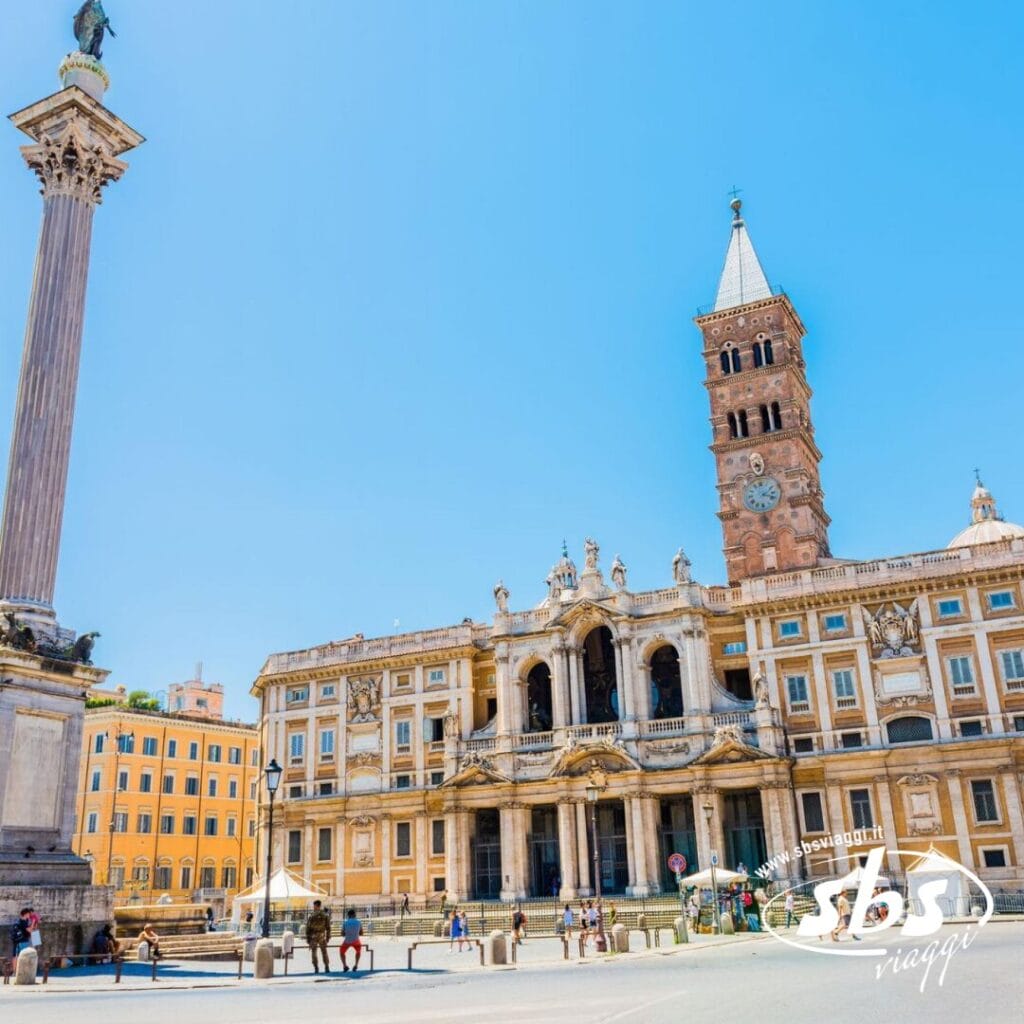 Una basilica storica con un alto campanile si erge accanto a una colonna in una piazza soleggiata, catturando l'essenza di Roma, Caput Mundi. Il cielo è limpido e azzurro.