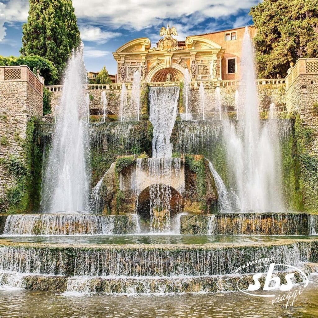 Una fontana a più livelli con acqua che cade a cascata da strutture in pietra, incastonata tra gli alberi e con un edificio storico sullo sfondo, offre uno scorcio del fascino senza tempo di Roma durante il tuo tour della Città Eterna.