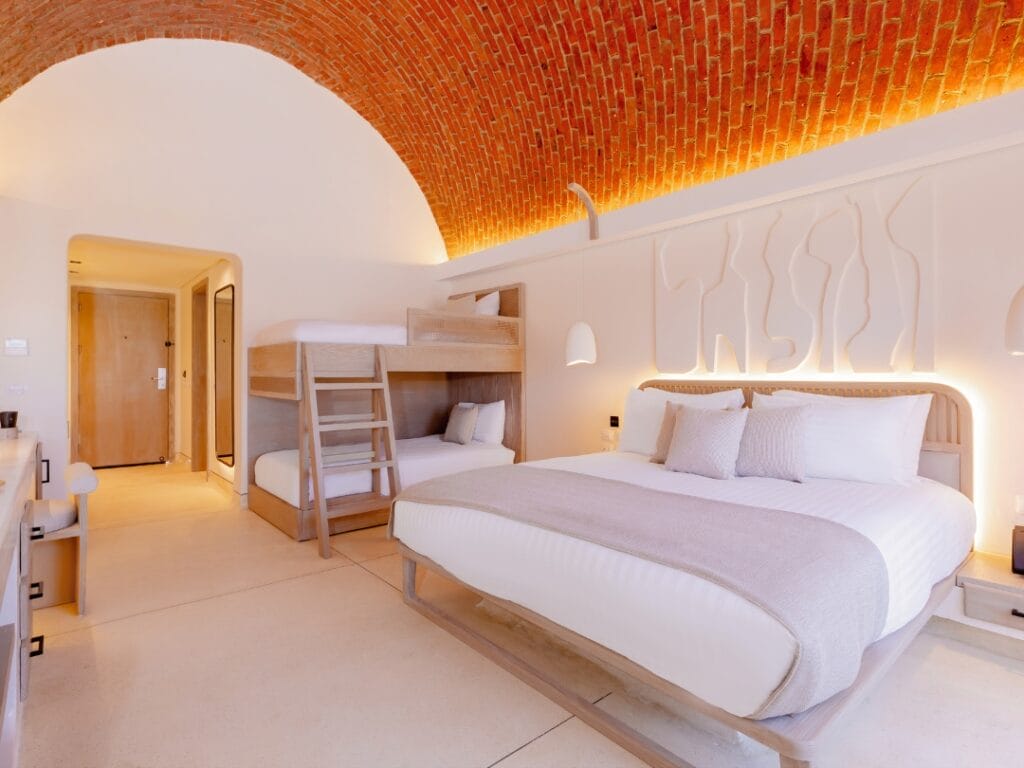 Provate il fascino di una camera al Sunrise Anjum Resort, dove un letto grande e un letto a castello sono sistemati sotto un soffitto a volta in mattoni illuminato da luci calde. Questo rifugio minimalista nel nostro resort a 5 stelle unisce comfort e stile per un soggiorno indimenticabile.