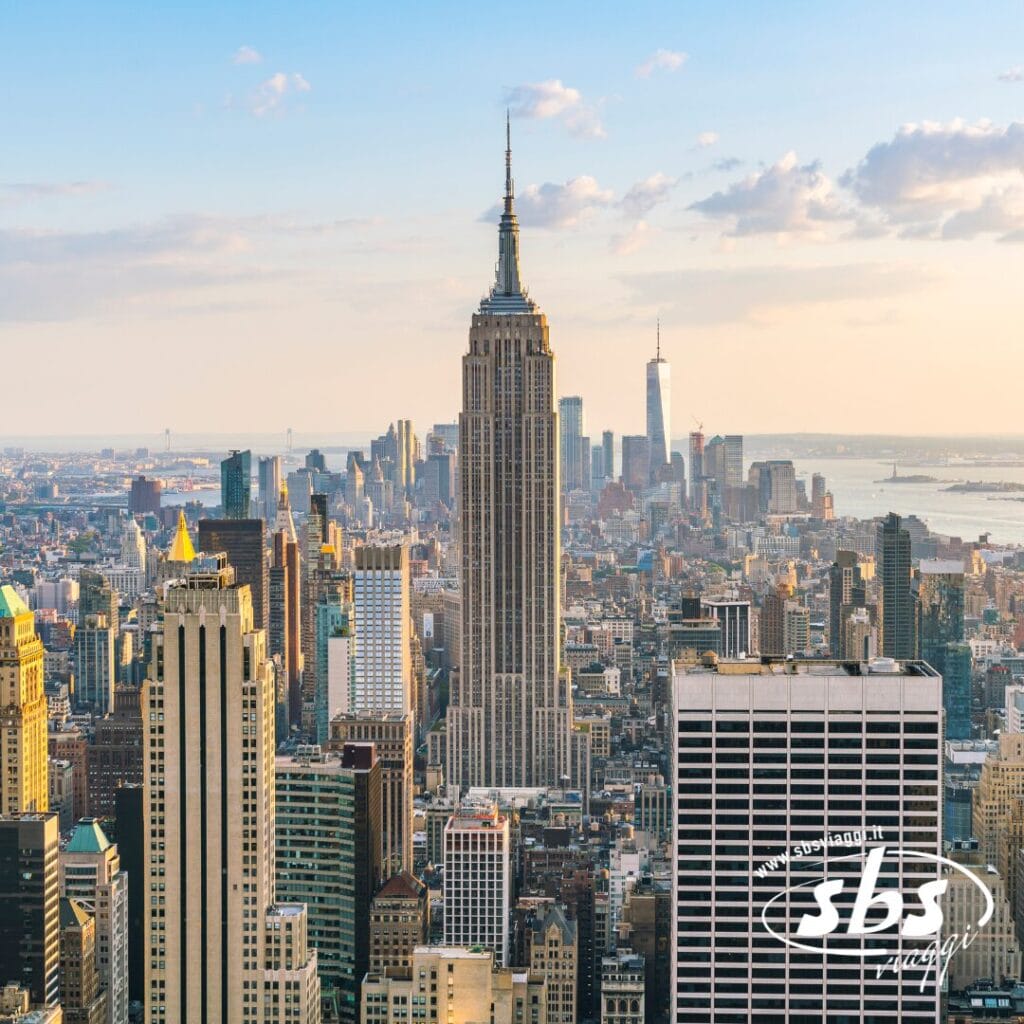 Vista aerea dello skyline di New York City con l'Empire State Building al centro e altri grattacieli sotto un cielo parzialmente nuvoloso, perfetta per chi sta programmando un tour di New York.