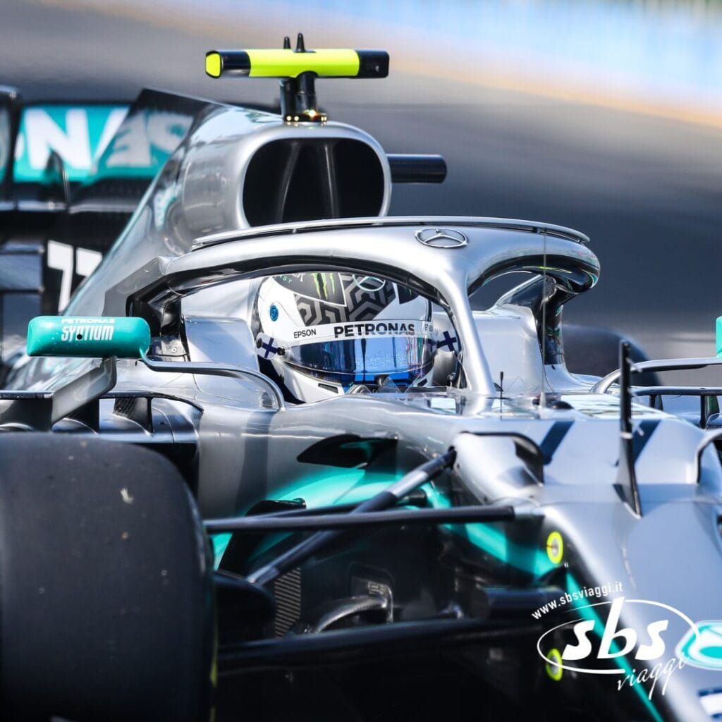 Una monoposto Mercedes di Formula 1 in pista mostra il pilota, con il casco visibile attraverso il dispositivo di sicurezza Halo: emozioni allo stato puro in pista mentre inseguono la vittoria fino al 2025.