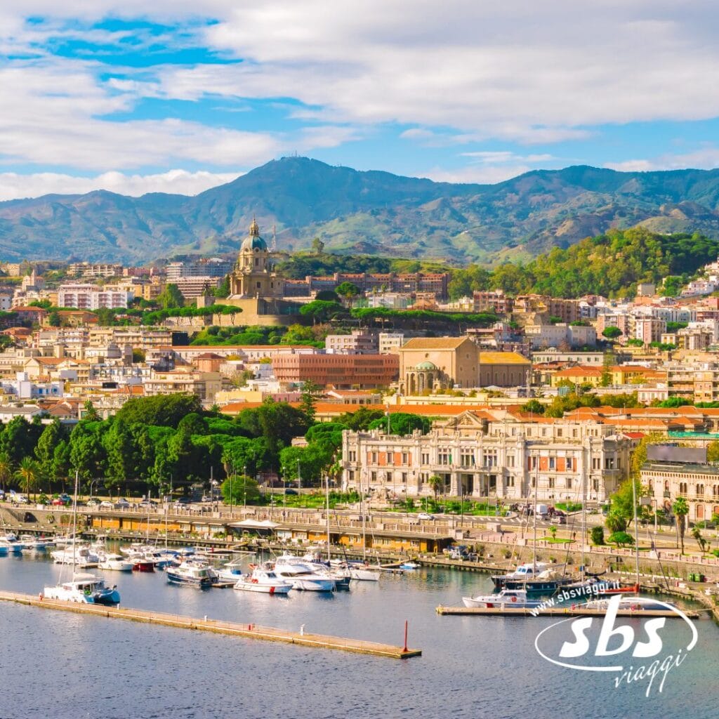Vista panoramica di una città costiera con barche ormeggiate nel porto, edifici storici e uno sfondo di lussureggianti colline verdi, perfette per un'avventura di Trekking Urbano. Godetevi le montagne sotto un cielo azzurro e limpido mentre vi imbarcate per il vostro viaggio a bordo di MSC Crociere.