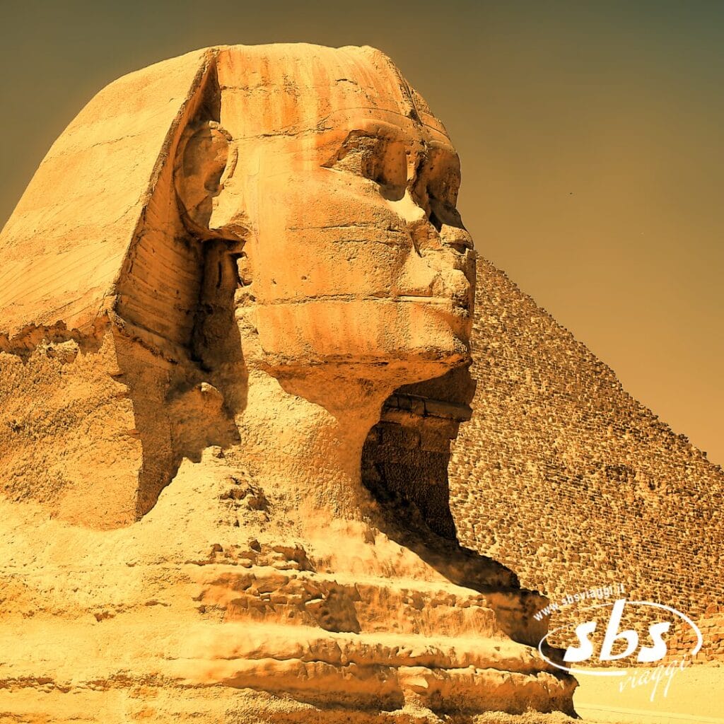 Una vista laterale ravvicinata della Grande Sfinge di Giza con una delle piramidi sullo sfondo sotto un cielo limpido, che cattura il mistero e la grandiosità duraturi dell'Antico Egitto vicino al vivificante Nilo.