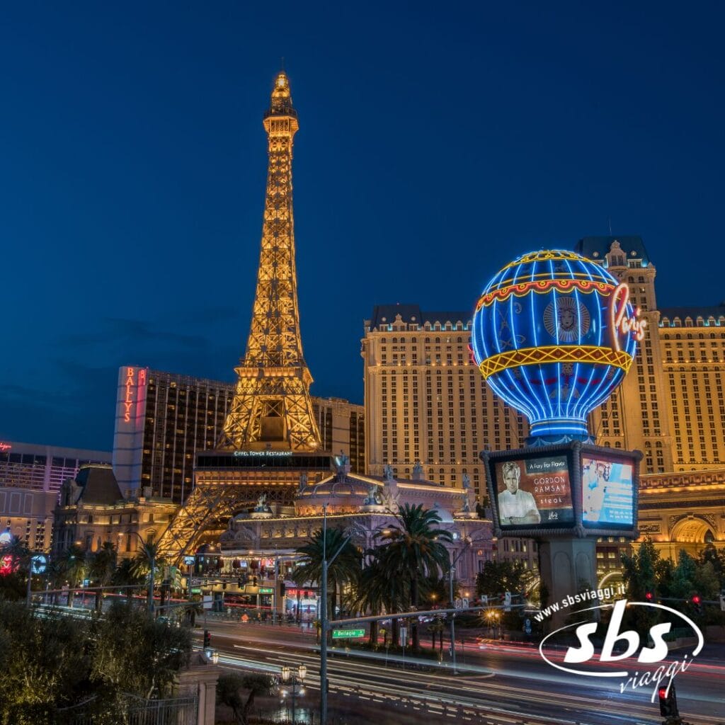 Vista notturna del Paris Las Vegas Hotel con la sua riproduzione della Torre Eiffel e l'insegna illuminata a forma di palloncino, circondato dalle luci della città e dal traffico: una scena vivace che ricorda la vita notturna di Los Angeles.