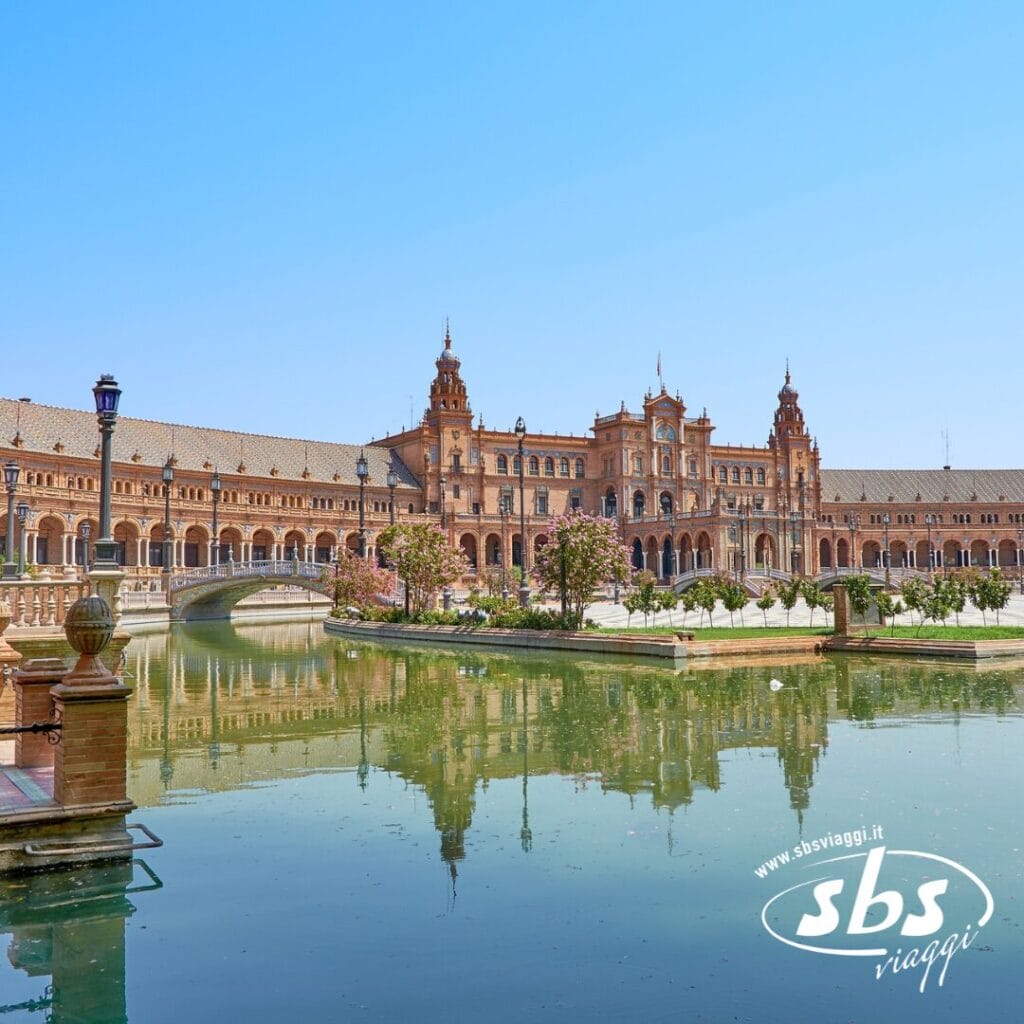 Plaza de España a Siviglia, in Spagna, è una meta turistica imperdibile in Andalusia. Si distingue per un imponente edificio semicircolare con una torre centrale, che circonda una piscina a specchio e ponti. Il logo
