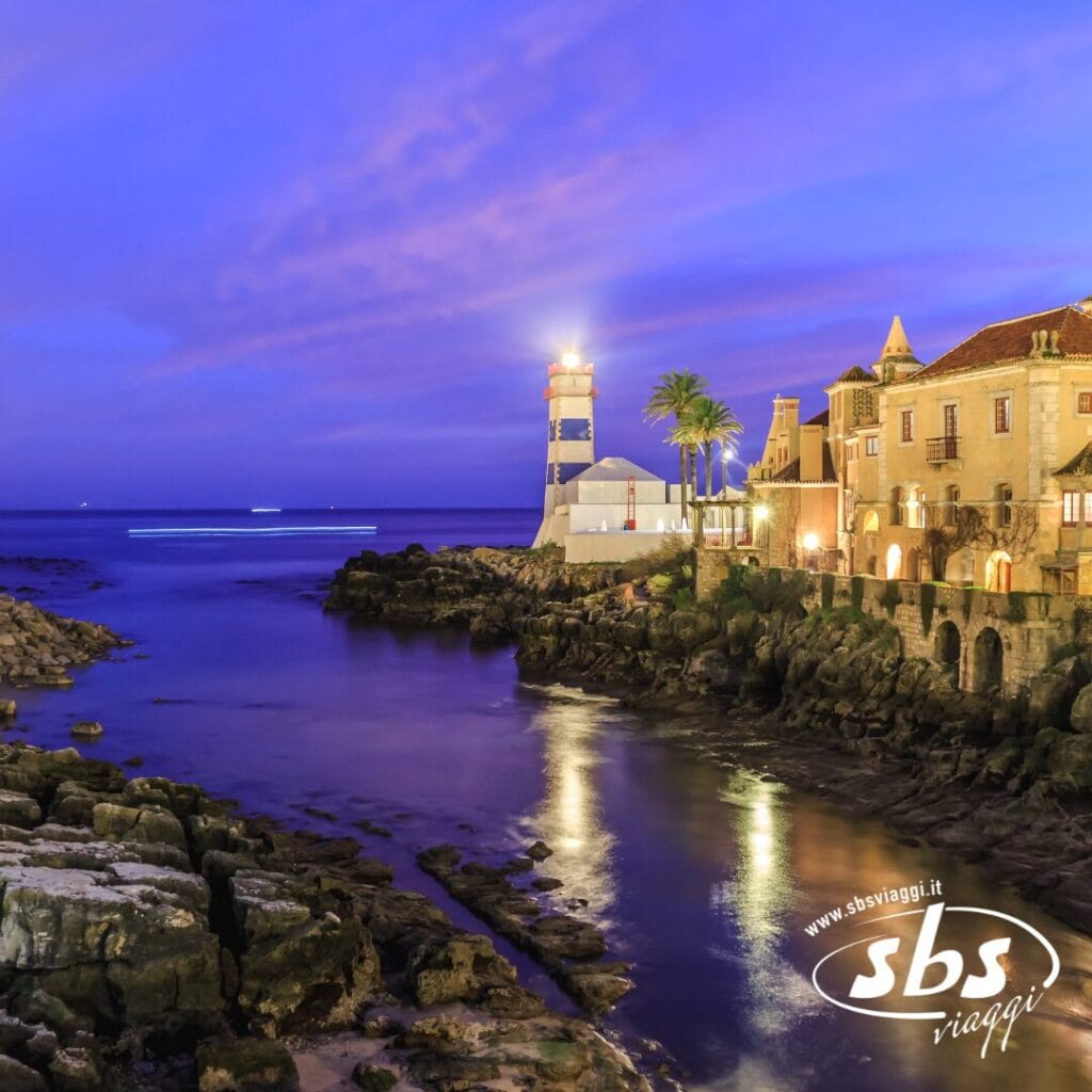 Paesaggio costiero al tramonto con uno sfondo incantevole durante il tour del Portogallo: un faro, edifici storici e palme che si riflettono elegantemente sul mare calmo.
