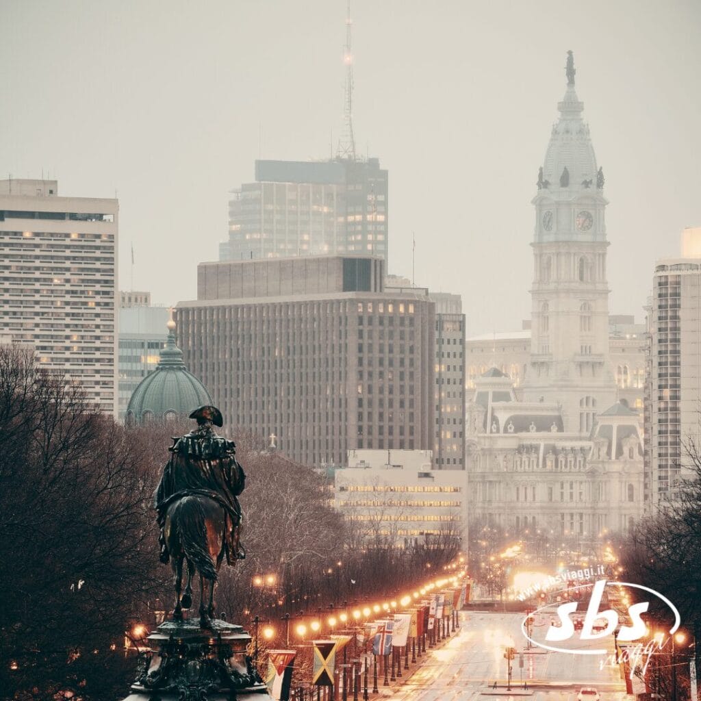 Una veduta della città di Filadelfia con la statua di Washington, strade alberate e il municipio sotto un cielo nuvoloso.